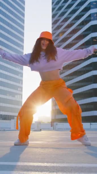 垂直录像 一个有趣的女孩在玻璃办公楼的背景下表演很酷的舞蹈 音乐视频嘻哈和霹雳舞表演的概念 青少年亚文化当代编舞 — 图库视频影像