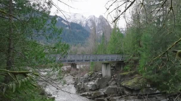 一座乡村的桥跨越了华盛顿荒野中一条奔腾的河流 雄伟的山峰高耸入云 体现了冒险精神 4K镜头 视频剪辑