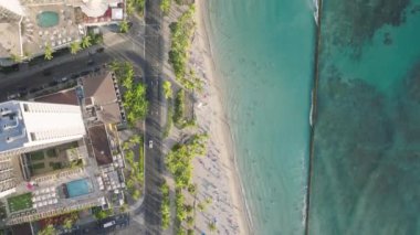 Bu hava manzarasında Oahu, Hawaii, ABD 'deki Waikiki Sahili, kumlu kıyı şeridi, turkuaz suları ve kıyı boyunca uzanan yüksek binaları yer alıyor..