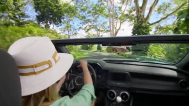 Saçında rüzgar olan bir kadın Oahus 'un yemyeşil ortamlarında üstü açık arabasıyla gezmekten zevk alır. Canlı ve özgür hisseder. 4K görüntü. 