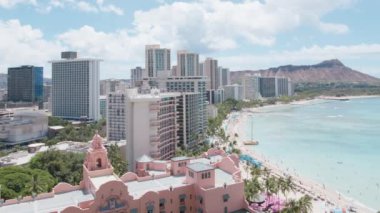 Waikiki Sahili 'nin altında parlak mavi bir gökyüzü var. Sörfçüler ve yüzücüler Oahu' nun el değmemiş turkuaz sularının keyfini çıkarıyorlar. 4K görüntü. 