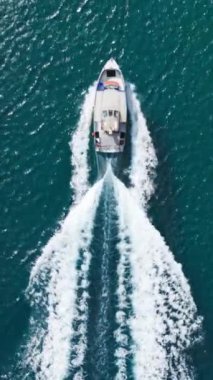 Yukarıdan yakalanan bir sürat teknesi Hawaii 'nin zengin mavi sularından geçiyor ve arkasında okyanusu aşan köpüklü bir uyanış bırakıyor.. 