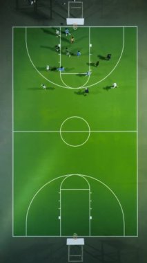 Yeşil sahada basketbol maçının havadan görünüşü ve hareket halindeki oyuncular. Yukarıdan vurulmuş. Anahtar sözcükler anten, basketbol, oyuncular, yeşil kort, açık hava, akşam, hareket, üst görünüm