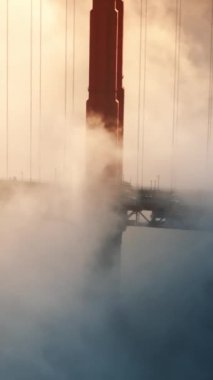Golden Gate Köprüsü 'nün dikey görüntüsü yoğun sis tarafından kısmen gizlenmiş, sislerin üzerindeki ikonik yapısını gözler önüne seriyor, Batı Yakası' nda nefes kesici ve görkemli bir manzara yaratıyor.