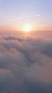 Kendinizi bulutların dingin güzelliğini ve havadan bakıldığında altın bir gündoğumunu gösteren nefes kesici dikey bir videoya daldırın. Sakin ve manzaralı görüntüler için mükemmel.