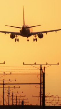 Gün batımında yaklaşım ışıklarıyla bir uçağın iniş yaptığı görülüyor. Sahne seyahat, havacılık ve doğa meraklılarının güzelliğinin tadını çıkarması için mükemmel. Gökyüzündeki huzurlu bir anı yakalamak için.