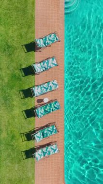 Güneşli bir günde havuz kenarındaki altı şezlongun havadan çekilmiş görüntüleri, deniz kenarında rahatlama ve rahatlama sahneleri, gölgeler. Tazelenmek için ortam mükemmel.
