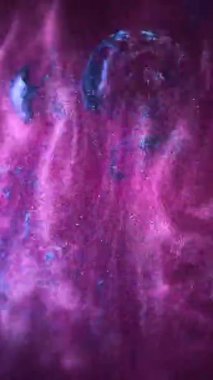 Suda dönen mor ve mavi boyaların hipnotik hareketi dikey video çerçevelerinde görüntülenir. Büyüleyici ve görsel olarak büyüleyici bir sıvı dans sergilerler.