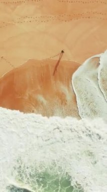 Dikey ekran: Bir hava dikey video dalgalarla sahilde balık tutan bir adamın sakin bir sahnesini çeker. Huzurlu kıyı manzarası huzur verici ve izole bir manzara sunuyor. Rahatlamak için ideal.