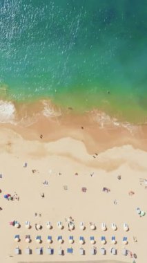 Dikey ekran: Turkuaz suları, yumuşak dalgaları, altın kumlu kıyıları olan sakin bir sahilin büyüleyici hava manzarası, barışçıl sahil görüntüsü için mükemmel. Hava fotoğrafçılığı veya video için ideal