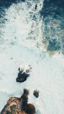 Portekiz, Nazare 'deki kayalık kıyı şeritlerine çarpan ve doğanın ham gücünü gösteren çarpıcı hava perspektifini tecrübe edin. Video dikey görüntüleme için optimize edilmiştir