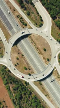 Dikey Ekran: Olağanüstü bir 4K hava görüntüsü, modern kentsel altyapı ve ulaşım mühendisliği sergilenen dikey bir ekranda, dairesel bir otoyol kavşağında trafik akışını yakalıyor