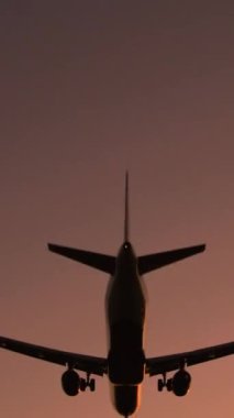 Günbatımında çarpıcı bir gökyüzüne inen uçağın büyüleyici dikey videosu seyahat içeriği için mükemmel, uçuşun ihtişamını ve barışçıl alacakaranlık renklerini gözler önüne seriyor.