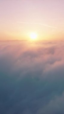 Dikey Ekran: Çarpıcı bir dikey video bulutlardan oluşan bir battaniyenin üzerinde nefes kesici bir gündoğumu yakalar. Arka plan ve doğa sahneleri için mükemmel. Sabah gökyüzünün sakin ve huzurlu bir görüntüsünü sunuyor.