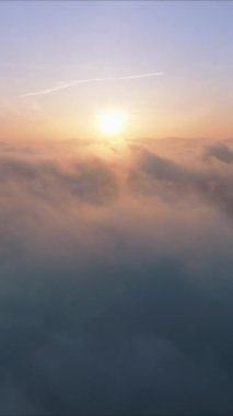 Dikey ekran: Dikey bir videoda çekilen bulutlar denizi üzerinde gün batımının çarpıcı hava görüntüsüne hayret edin. Bu sakin ve sakin manzara huzurlu ve rahatlatıcı arka planlar için mükemmeldir.