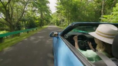 Üstü açık arabadaki neşeli bir kadın Oahus 'un yemyeşil yollarında esintiyi hisseder, Hawaii macerasının özünü yakalar. 4K görüntü. 