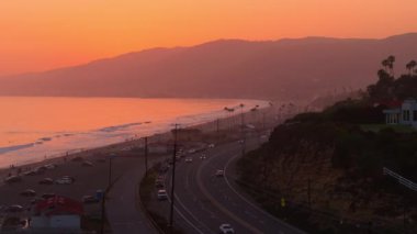 Günbatımında Malibu, California 'nın güzelliğini gösteren nefes kesici bir hava görüntüsü, büyüleyici sahil şeridini, dağları ve Pasifik Sahil Otobanı' nı altın sarısı renklerde gösteriyor.