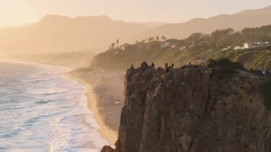Kaliforniya 'daki Malibus sahil şeridinin çarpıcı hava manzarası güneşin doğuşunun dingin güzelliğini altın bir ışıkla kayalıkları ve plajları aydınlatarak huzur verici bir manzara yaratıyor.