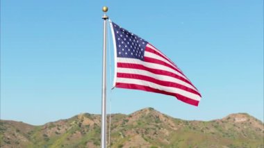 Yıldız ve çizgileriyle Amerikan bayrağı ulusal gururu, önemli değerleri ve ulusal bayramları temsil eder. Gururla uçar dağların ardında ve berrak mavi gökyüzünde