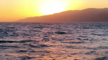 Kaliforniya 'daki Malibu okyanus dalgaları üzerinde nefes kesici günbatımının tadını çıkarın. Doğanın sıcacık ve altın renklerinde güzelliğini yakalayın. Huzurlu ve pitoresk bir manzara.