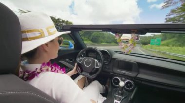 Neşeli bir kadın, Oahu 'nun verimli ve tropikal ortamını keşfedip ada atmosferini kucaklayan üstü açık arabasından el sallıyor. 4K görüntü. 
