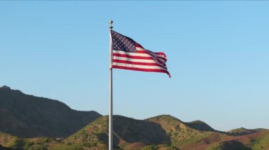 Görkemli bir Amerikan bayrağı, gün doğumunun ya da gün batımının dingin ışığıyla bir dağ zeminine vurularak aydınlanır. Bu da onu Bağımsızlık Günü gibi vatanseverliğin sembolü yapar.