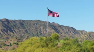 Amerikan bayrağının ihtişamlı dağlarla dalgalanması, vatanseverliğin ve doğal güzelliğin simgesi, Bağımsızlık Günü ve Başkanlık Günü sembolizmi için ideal..
