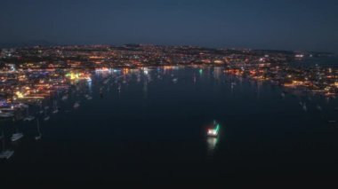 4K hava görüntüsü, Kaliforniya, ABD 'deki Newport Sahili Noel Gemisi Geçidi' nin canlı ışık ve şenlikli atmosferini ve geceyi aydınlatan sayısız süslü tekneyle gösteriyor..