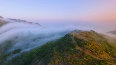 Büyüleyici Malibu dağları, güneş doğarken ya da batarken Kaliforniya 'da gün batımında sisle kaplanmış ve şafak veya alacakaranlıkta huzurlu bir ortam yaratan barışçıl bir hava yayar.
