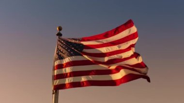 Amerikan bayrağının büyüleyici bir fotoğrafı, vatanseverliği, bağımsızlığı ve gururu simgeliyor, renkli bir günbatımı gökyüzüne karşı kurulmuş. Vatansever etkinlikler ve başkanlık törenleri için ideal.