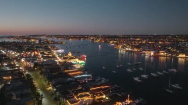 California 'daki nefes kesici Newport Sahili Noel Gemisi Geçit Töreni' ni yaşayın. Gece gökyüzünde parıldayan neşeli ışıklarla süslenmiş tekneler büyülü bir ortam yaratıyor.