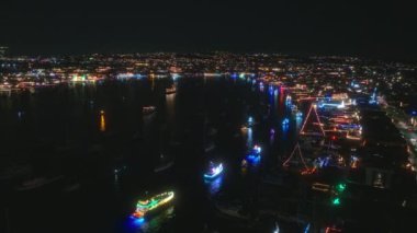 California 'daki Newport Sahili Noel Gemisi Yürüyüşü' nün büyüleyici hava manzarasını izleyin. Büyülü ışıklarla aydınlatılan şenlikli tekneler, canlı bir gece sahnesi yaratıyor.