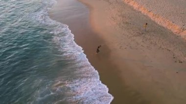 Çarpıcı 4K hava görüntüsü Newport Sahili, Kaliforniya 'nın sakin sahili, kumlu plajları ve sakin dalgalarıyla güzelliğini gösteriyor. Bu resim sahnesinde bir insan kıyı boyunca yürür.