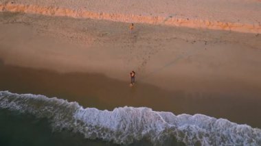 Newport Beach, California, ABD - 17 Aralık 2024: Newport Beach, Kaliforniya 'nın günbatımında çekilen bir drone görüntüsü dalgaları, kumlu kıyıları ve resimli okyanus manzaralı sakin bir kıyı manzarasını gösteriyor.