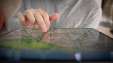 Bir adamın elinin tabletle etkileşim halinde olduğu, detaylı bir haritaya odaklandığı, navigasyon ve keşifteki modern teknolojiyi gösteren yakın plan.