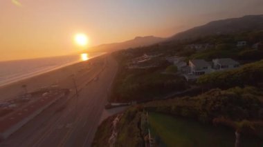 FPV insansız hava aracı büyüleyici ve görkemli Malibu kıyı şeridinin üzerinde zahmetsizce süzülüyor, martıları yavaş çekimde yakalıyor ve kesinlikle nefes kesici bir gün batımına karşı.
