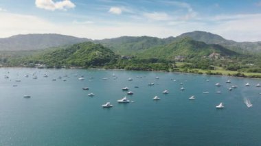 Santa Cruz, Kosta Rika 'nın bu hava görüntüsü yeşil tepeleri yemyeşil suları, turkuaz suları ve körfezdeki tekneleri sergiliyor ve bunu turizm ve macera için büyüleyici bir yer haline getiriyor.