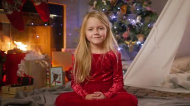 Kırmızı kadife elbiseli genç bir kız Noel kutlamalarının ortasında zarif bir şekilde oturur ve tatil sezonunun ruhunu yakalar. 4K görüntü. 