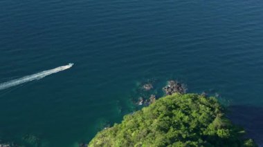Havadan çekilen bir görüntü, canlı, yemyeşil sularda ustalıkla gezinen bir tekneyi yakalar.