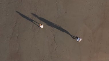 Sevgi dolu bir baba ve küçük oğlu huzurlu bir kumsalda geziniyor, siluetleri dalgalara karşı dizilmiş, derin bağlantılarını ve doğada kaliteli zaman geçirmenin sevincini yakalıyor.