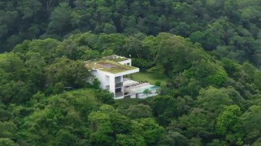 Bu hava manzarası Kosta Rika 'nın yemyeşil ormanlarında çarpıcı bir modern evi gösteriyor. Güzel yeşil çevresini ve sakin atmosferini aydınlatarak mükemmel bir kaçış ortamı yaratıyor.