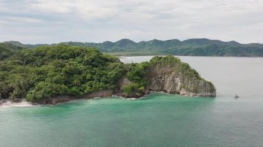 Puntarenas, Kosta Rika 'nın nefes kesen bu görüntüsü büyüleyici yeşil tepeleri, kayalık kıyı şeridini ve bu cennetin sunduğu sakin turkuaz suları güzel bir şekilde yakalıyor.