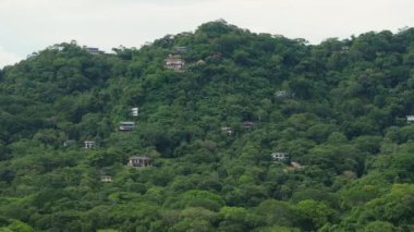 Puntarenas, Kosta Rika 'nın göz kamaştırıcı manzarasını, yemyeşil ve tepe kenarındaki evleri ile keşfedin. Bu bölgenin özünü yakalayan 4K hava görüntülerinde güzelce sergilenmektedir.