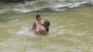 Yürek ısıtan bir sahnede, bir baba neşe içinde oğlunu nehrin yukarısına kaldırır ve güzel bir bağ ve mutluluk anı yaratır.