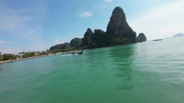Krabi, Tayland - 29 Kasım 2024: FPV insansız hava aracı Krabi turkuaz sularında hızla ilerleyen geleneksel uzun kuyruklu bir tekneyi yakından takip ediyor..