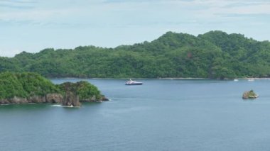 Huzurlu suların, yemyeşil yemyeşil yemyeşil bir adanın ve sakin manzarada süzülen bir teknenin olduğu nefes kesici bir okyanus manzarası. Doğa aşıkları ya da macera arayanlar için idealdir. Keşfedin