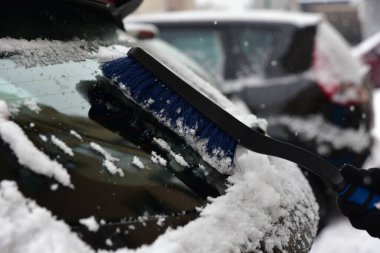 Araba penceresinden bir fırçayla kar temizleniyor