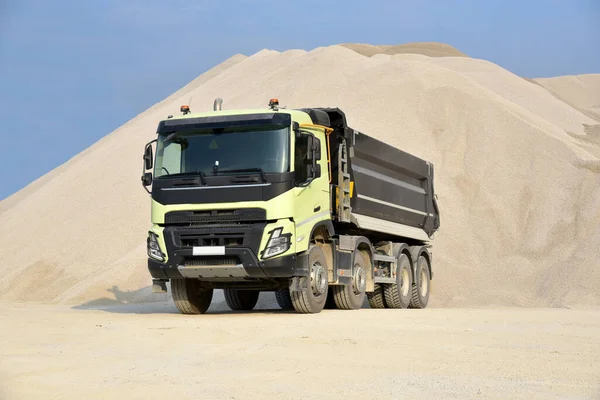 A large dump truck is parked in a quarry