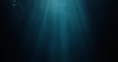 Sualtı tanrısı ışınlarının okyanus yüzeyini delip geçen, dalış, şnorkelleme ve yaz maceraları için büyüleyici ışık demetleri titreşimli VFX arka planıyla 4K yavaş çekim görüntüsü..