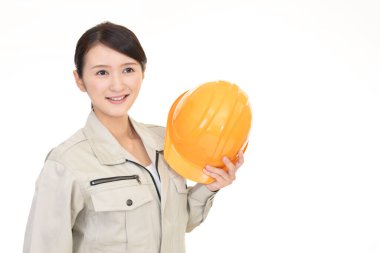 Kasklı, gülümseyen bir kadın işçi.